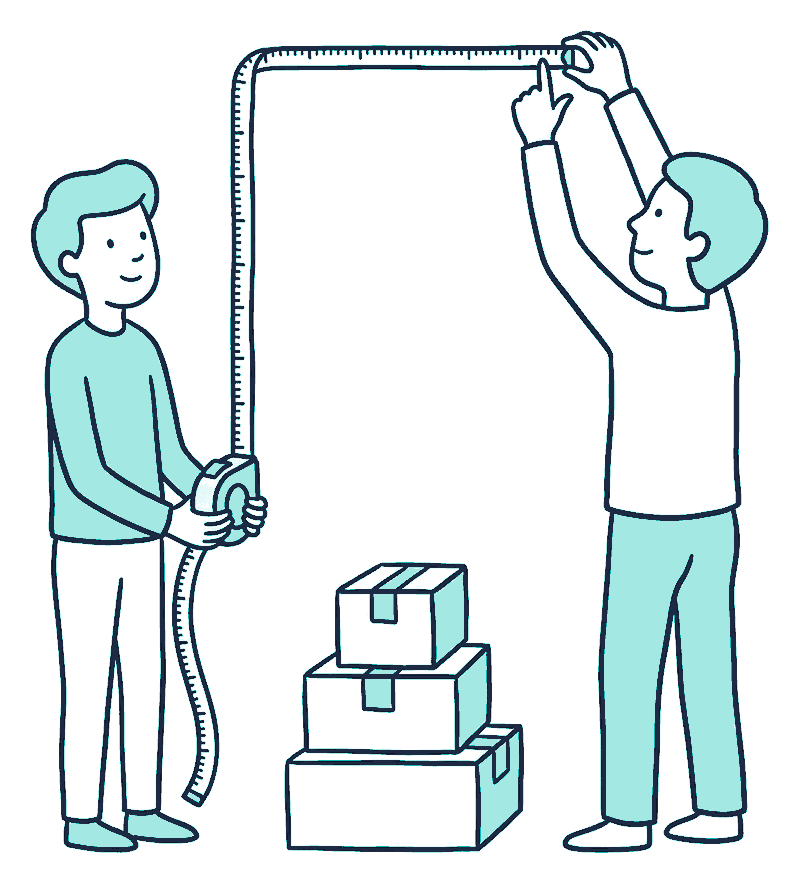 Two people stretch a tape measure up a tall wall, marking the wide gap above a short stack of boxes