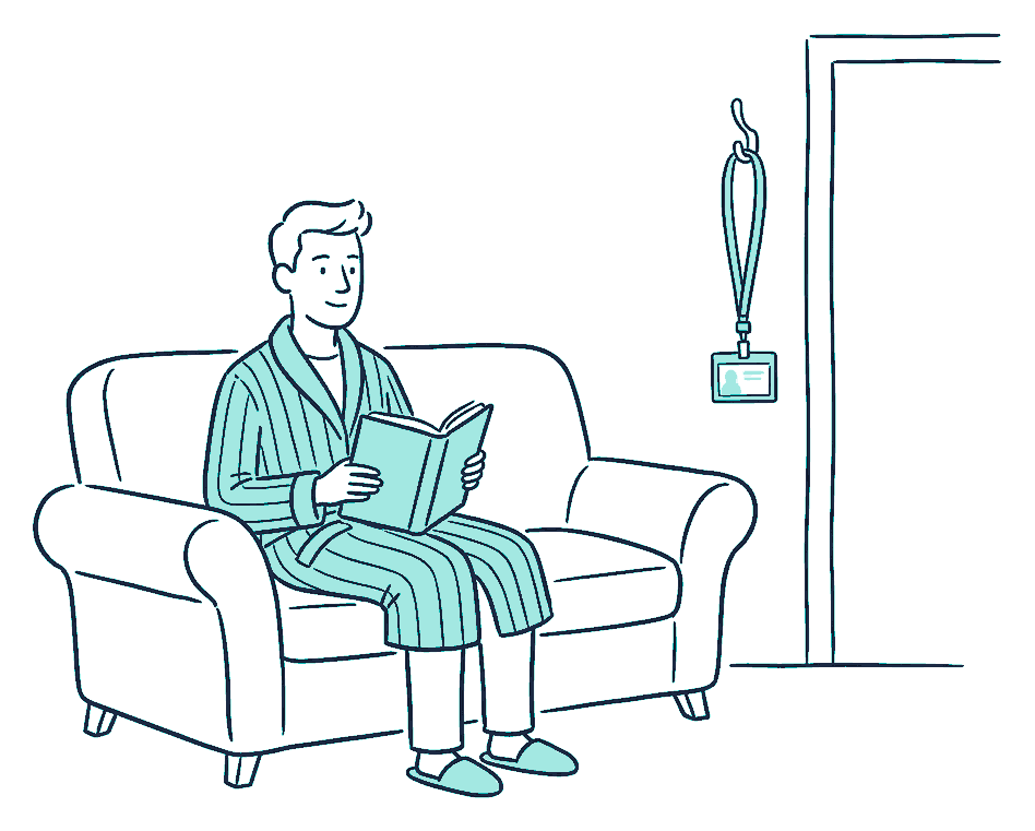 A man in a dressing gown sits on a couch while his work lanyard hangs unused on a door hook