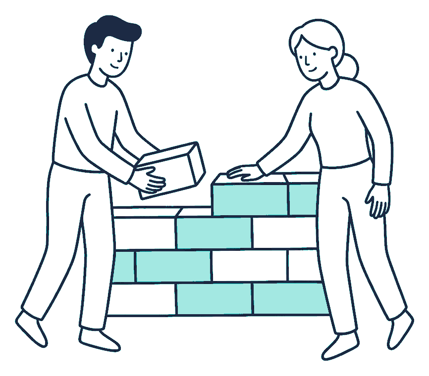 Two people fit interlocking blocks together into a low wall, one steadying the top row