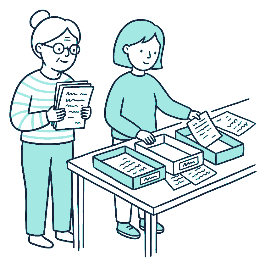 An older person and an adult child sort scribble-covered papers into three separate trays on a dining table