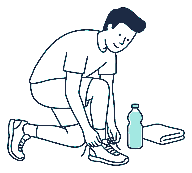 A man laces his running shoes on a park path while a water bottle and towel rest on the grass