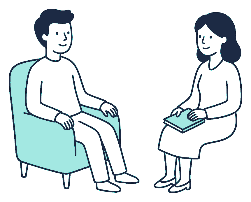 A person sits in an armchair opposite a counsellor who listens with a notepad resting closed on their lap
